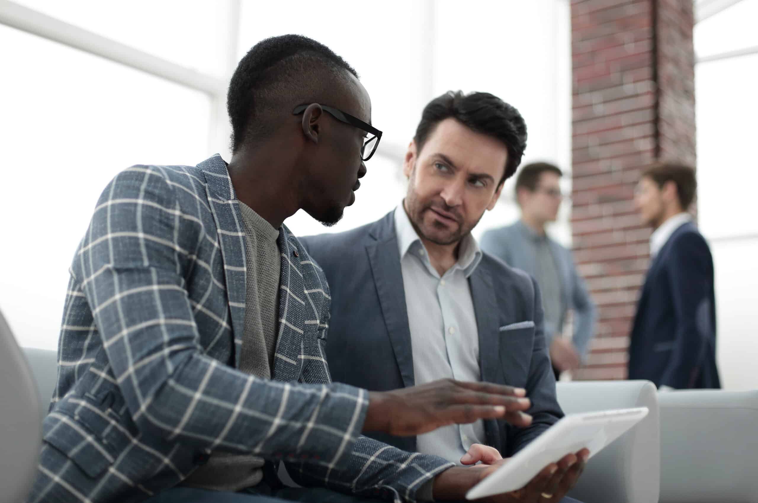 two businessmen use a digital tablet